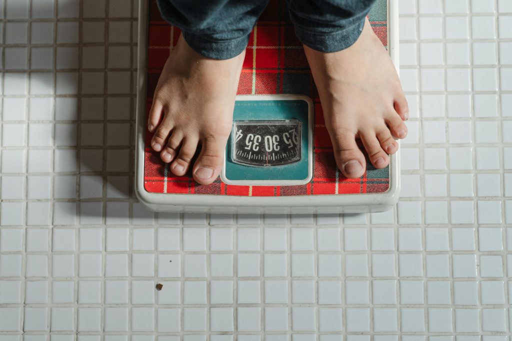 Person standing barefoot on a red scale to measure weight loss