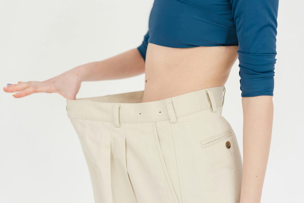 Woman stretching out pants that are too big because of weight loss